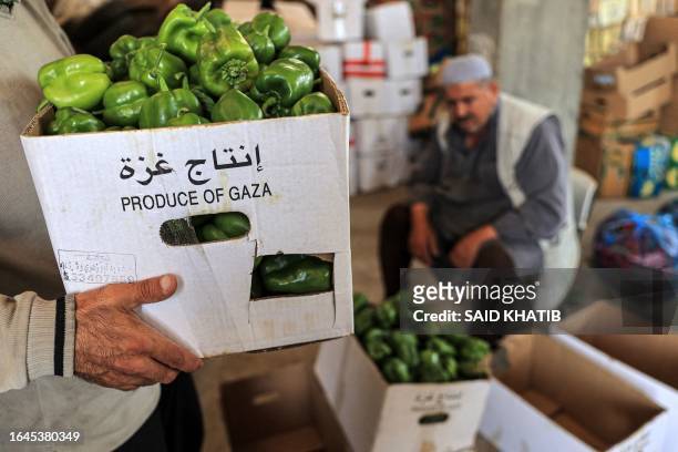 Palestinian workers unload boxes of produce that were originally headed to Israel via the Kerem Shalom commercial border crossing, at a warehouse in...