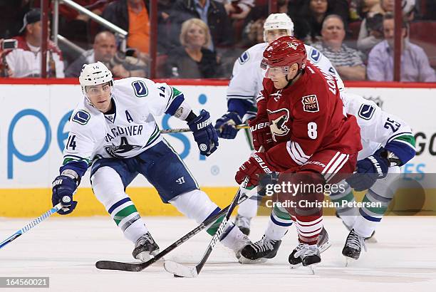 Matthew Lombardi of the Phoenix Coyotes looks to pass the puck pressured by Alex Burrows of the Vancouver Canucks during the NHL game at Jobing.com...