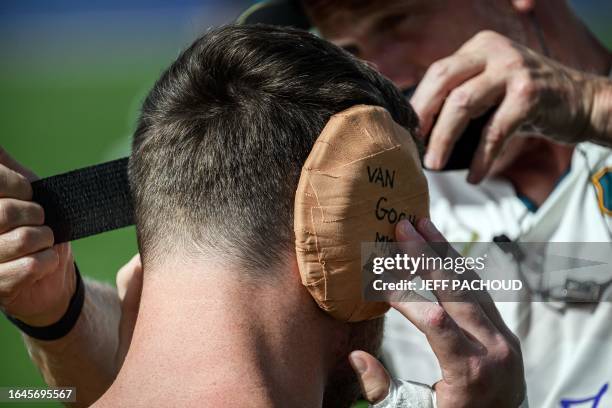 Australia's lock Nick Frost puts on an ear protection bearing words "Van Gogh" before taking part in a training session at Roger Baudras Stadium in...