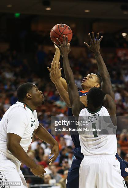 Joseph Bertrand of the Illinois Fighting Illini goes up for a shot over Durand Scott and Reggie Johnson of the Miami Hurricanes in the first half...