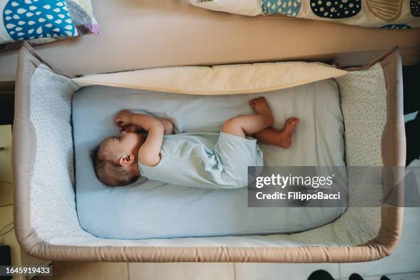 a little baby is sleeping in his crib next to the parents' bed - babysäng bildbanksfoton och bilder