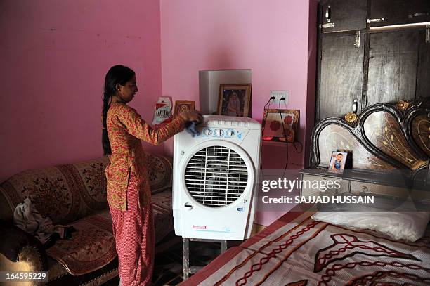 An Indian resident cleans an air cooler at her residence in the village of Malpur in the northern Indian state of Uttar Pradesh on December 16, 2012....