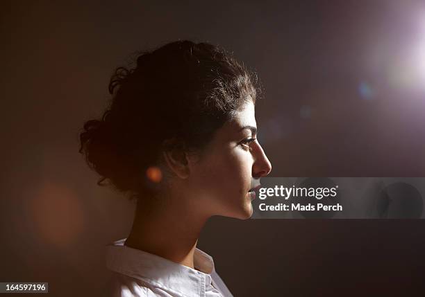 young woman with flare behind her - profile stock-fotos und bilder