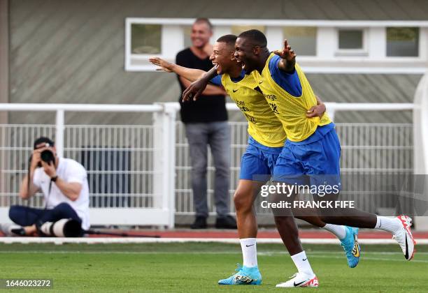 France's forward Kylian Mbappe and France's forward Marcus Thuram react at the end of a training session as part of the team's preparation for...