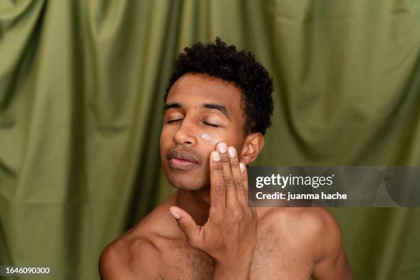 man applying facial cream. - applying cream stock pictures, royalty-free photos & images