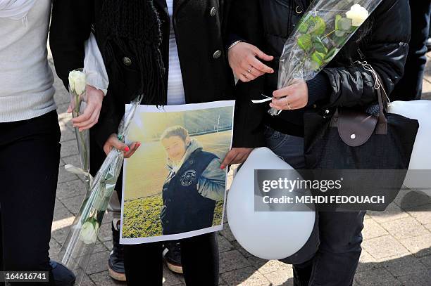Students, holding flowers and a portrait, mourn on March 25, 2013 during a ceremony and march in honour of Sylvain , a 15-year-old schoolboy stabbed...