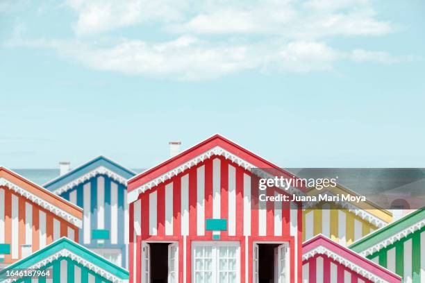 colorful striped and white houses on a beach. - portuguese culture stock pictures, royalty-free photos & images