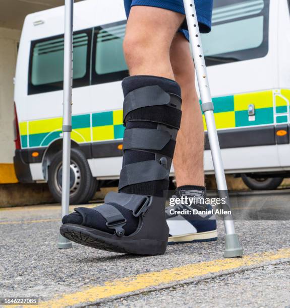 young man walking with leg brace and crutches - broken leg stock pictures, royalty-free photos & images