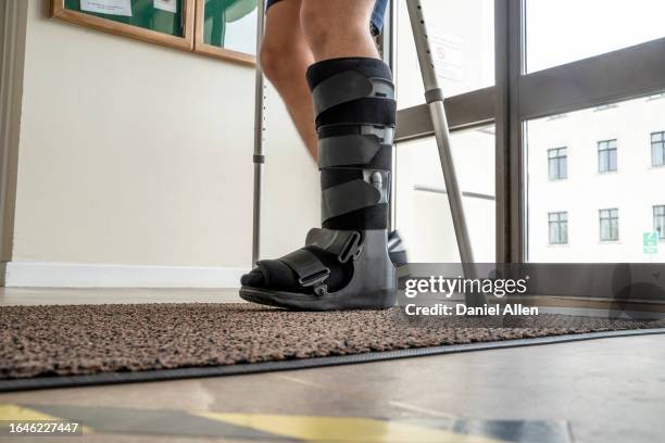 young man walking with leg brace and crutches - manschette stock-fotos und bilder