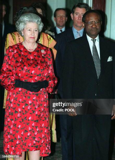 Queen Elizabeth II stands at attention alongside Commonwealth Secretary General chief Emeka Anyaoku of Nigeria, during the playing of Britain's...