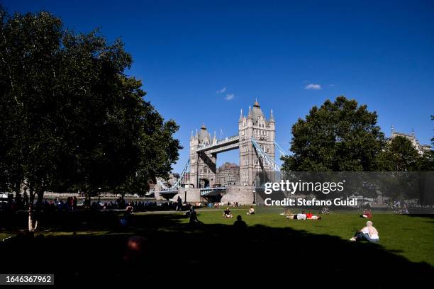 Tourists relax in Potters Fields Park in front of Tower Bridge on August 22, 2023 in London, England. London is the capital of England, many of the...