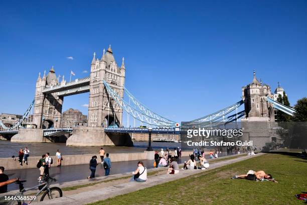 Tourists relax in Potters Fields Park in front of Tower Bridge on August 22, 2023 in London, England. London is the capital of England, many of the...