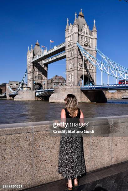 Woman looks in front of Tower Bridge on August 22, 2023 in London, England. London is the capital of England, many of the inhabitants, called...