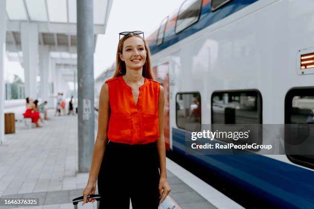 woman with suitcase strolls towards her train at the station - travel real people stockfoto's en -beelden