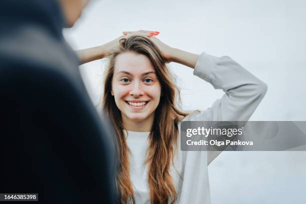 smiling young woman looks at camera standing behind her friend's shoulder - breaking up stock pictures, royalty-free photos & images