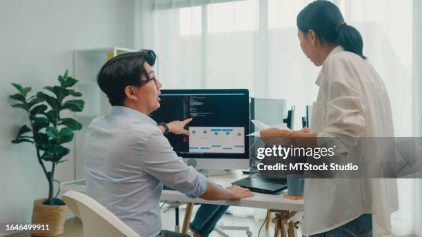group of asian people software developers using computer to write code sitting at desk with multiple screens at office. programmer development. - application programming interface stockfoto's en -beelden