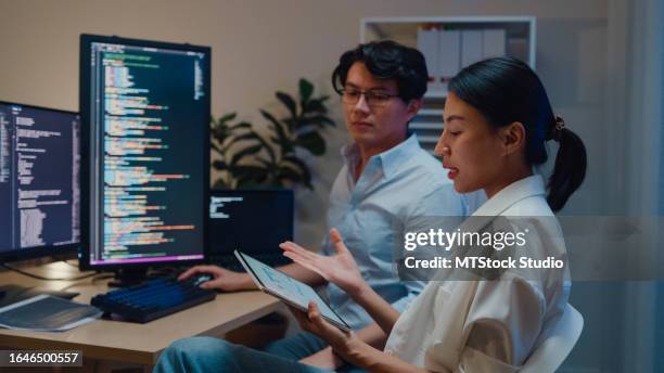 gruppo di sviluppatori di software di persone asiatiche che utilizzano il computer per scrivere codice seduti alla scrivania con più schermi in ufficio di notte. sviluppo programmatore. - programmazione televisiva foto e immagini stock