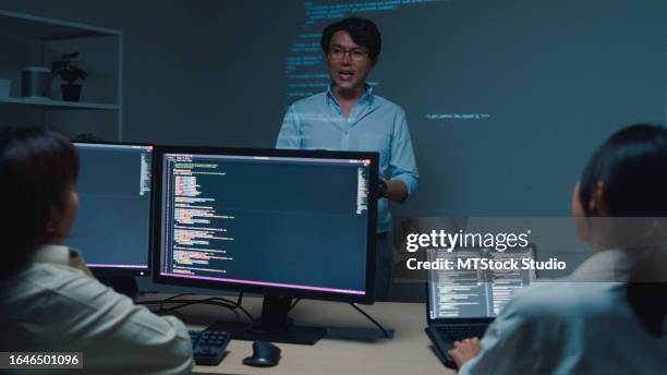 junger asiatischer mann, softwareentwickler, mentor, führungsmanager, der mit dem führungsteam spricht, das nachts im büro quellcode analysiert. entwicklung von programmierern. - python-programmiersprache stock-fotos und bilder