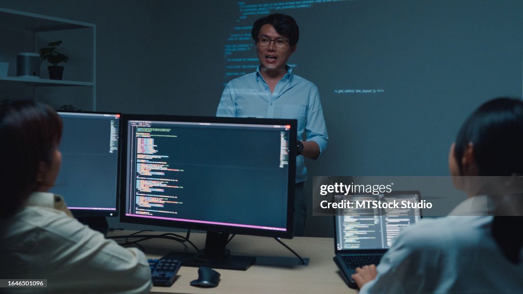Jeune homme asiatique développeurs de logiciels mentor leader manager parlant à l’équipe de direction analysant le code source au bureau la nuit. Développement de programmeurs.