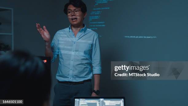 young asian man software developers mentor leader manager talking to executive team analyzing source code in office at night. programmer development. - mining conference stock pictures, royalty-free photos & images