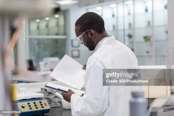 male technician works on nutritional supplements in lab - solutions chemistry stock pictures, royalty-free photos & images