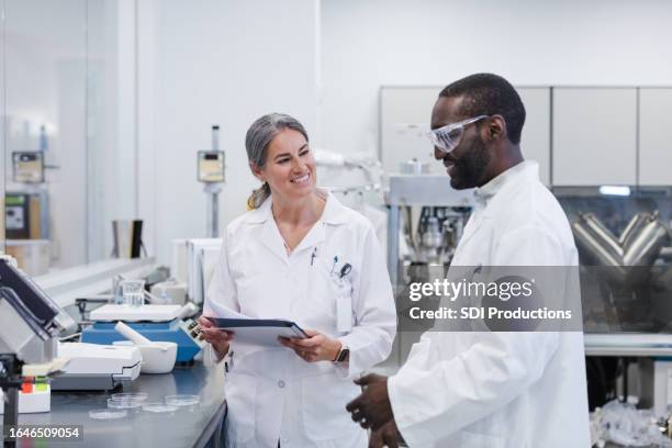 Female lab director smiles as male colleague reports experiment results