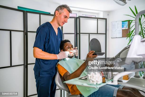 man checking his results in the dentist's office - plaque remover stock pictures, royalty-free photos & images