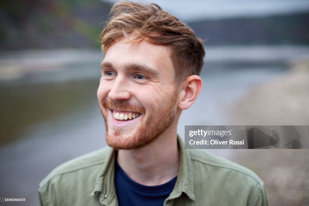 Happy young man at riverbank looking sideways
