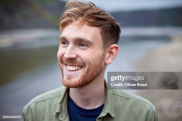 happy young man at riverbank looking sideways - sideways glance stock pictures, royalty-free photos & images