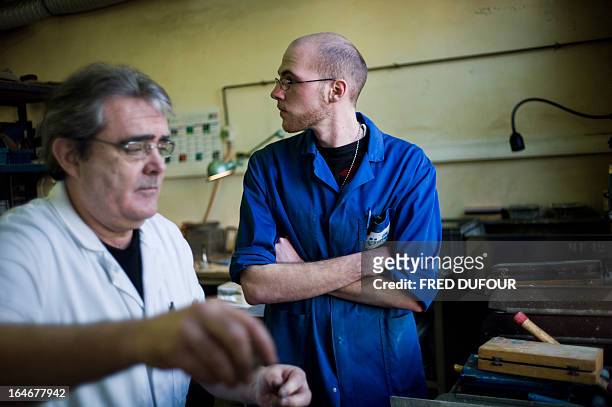 Young man working under a "generation contract" stands beside a senior employee on March 25, 2013 at the OPA-OPTICAD, an optical production and...