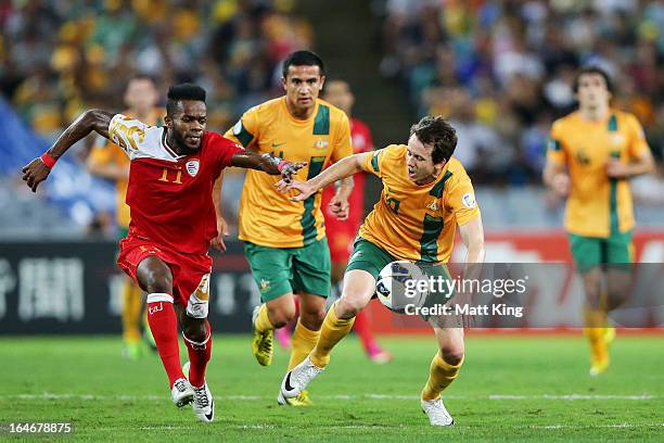 Robbie Kruse of the Socceroos is challenged by Saad Al-Mukhaini of Oman during the FIFA 2014 World Cup Qualifier match between the Australian...