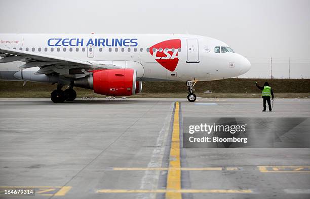 Member of the ground crew signal towards the flight deck of an Airbus A319 aircraft operated by Ceske Aerolinie AS airlines as it taxis at Vaclav...