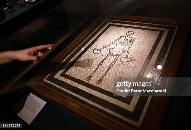 Visitor to the Life And Death In Pompeii And Herculaneum exhibition points at a mosaic of a skeleton at The British Museum on March 26, 2013 in...