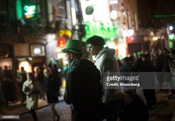People dressed in St. Patrick's day colors walk through the Temple Bar area late at night in Dublin, Ireland, on Friday, March 15, 2013. Ireland’s...