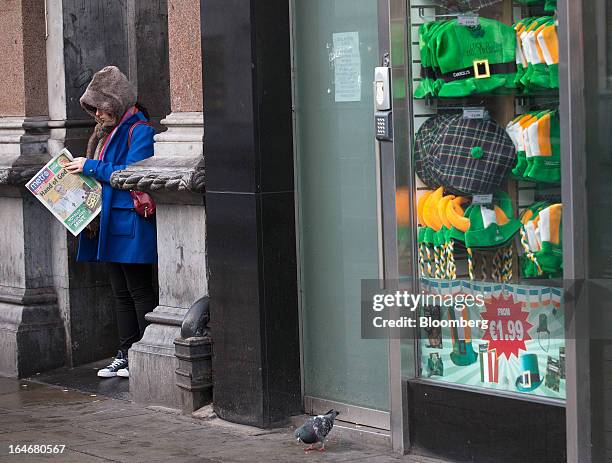 Woman reads a newspaper alongside a souvenir store selling Irish-themed goods in the Temple Bar area of in Dublin, Ireland, on Thursday, March 14,...