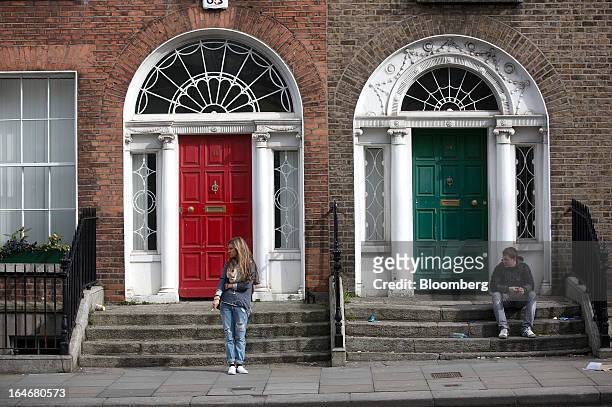 Man sits, right, and a women smokes a cigarette outside a Georgian property in Leeson Street in Dublin, Ireland, on Thursday, March 14, 2013....