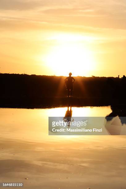 sunset over the river estuary in playa carrillo with a person crossing in the water in silhouette. - playa carrillo stock pictures, royalty-free photos & images
