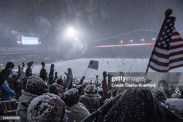 Fans of the United States national team cheer and wave flags as snow falls and the stoppage time period ends the game with a United States victory in...