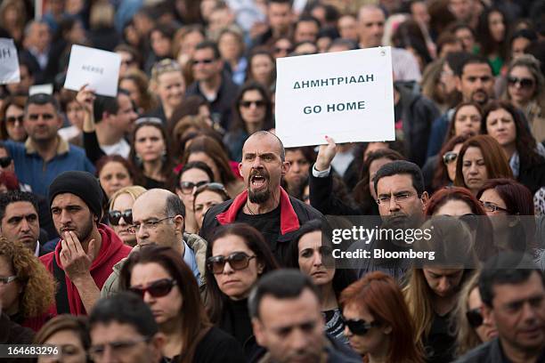 Demonstrators shout and wave a banner which reads "Demetriades go home," right, during a protest by bank workers outside the Cypriot central bank in...