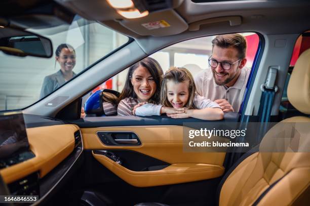 happy family enjoying while buying a car in a showroom. - test drive imagens e fotografias de stock