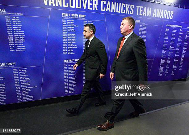 Vancouver Canucks general manager Mike Gillis and assistant general manager Laurence Gillman walk through the arena before their NHL game against the...