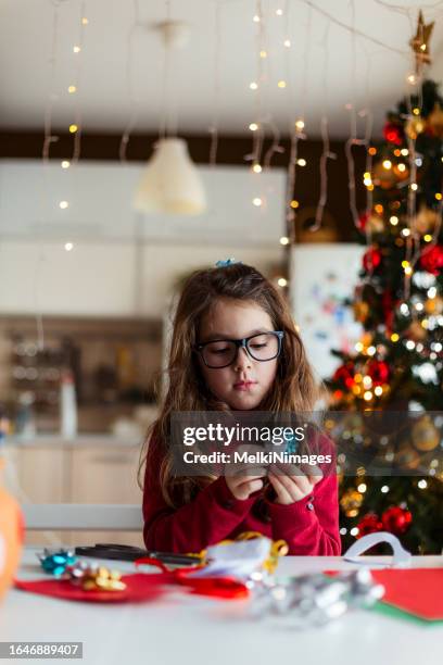 kreatives kind spielt mit gegenständen und bastelt weihnachtskarten und ornamente zu hause - bastelarbeit stock-fotos und bilder