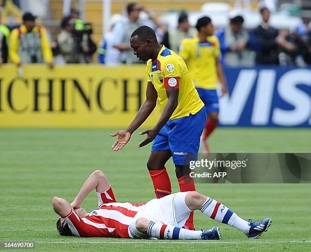 Ecuadorean defender Walter Ayovi tries to get Paraguayan forward Oscar Cardozo to stand up during their FIFA World Cup Brazil 2014 South American...