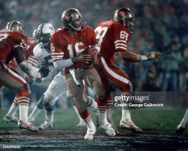 Quarterback Joe Montana of the San Francisco 49ers drops back to pass behind the blocking of offensive lineman John Ayers during Super Bowl XIX...