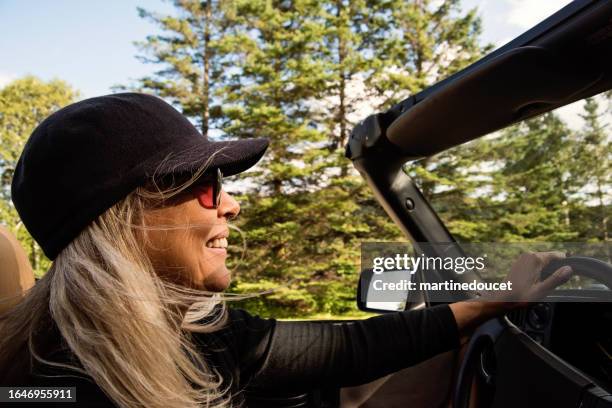 beautiful mature woman driving convertible car in country. - convertible car stock pictures, royalty-free photos & images