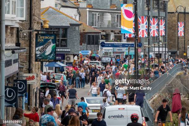 People walk along the harbour front at St Ives on August 21, 2023 in Cornwall, England.