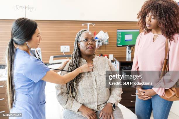 daughter waits as nurse checks mom's heart and lungs - casualty stock pictures, royalty-free photos & images
