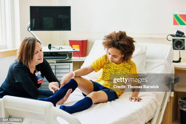 medium wide shot doctor examining soccer player in emergency room - notfallmedizin stock-fotos und bilder