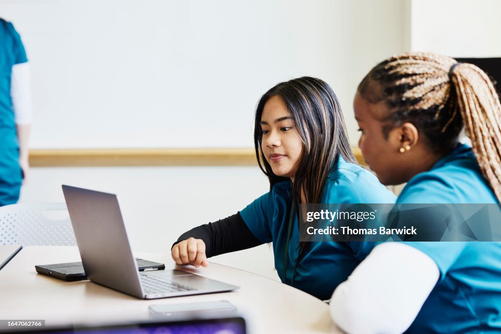 Medium shot nurses working on laptop during medical team meeting
