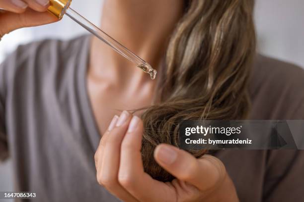 natürliches ätherisches bio-öl auf das haar auftragen - women haircare stock-fotos und bilder
